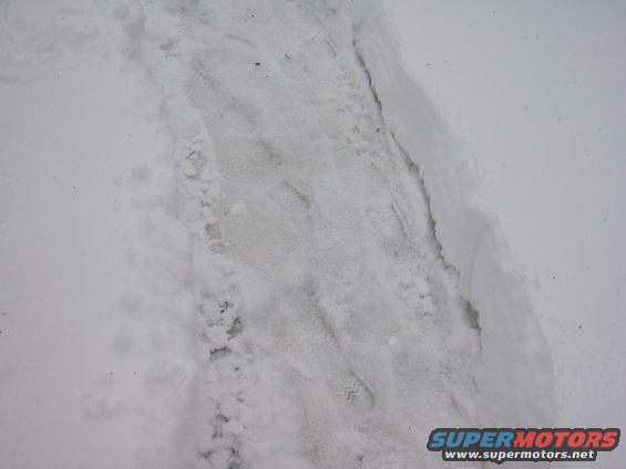 tire tracks and footprints in snow, with a watermark for Supermotors.net