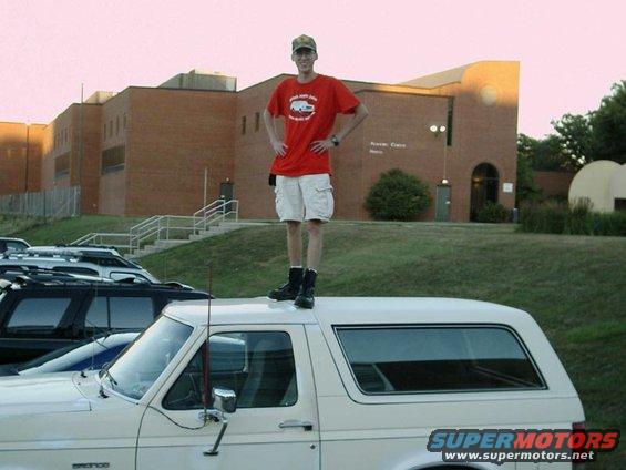 White 1988 Ford Bronco side view with man standing on roof