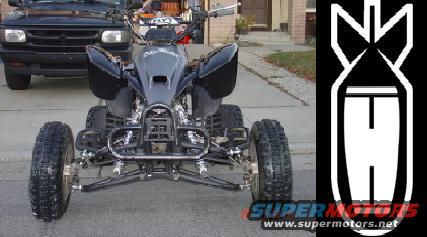 Black ATV front view, parked on asphalt, with a black truck behind it