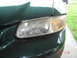 1997 Dodge Grand Caravan - The driver's side headlight assembly of a green minivan shows signs of age and wear.