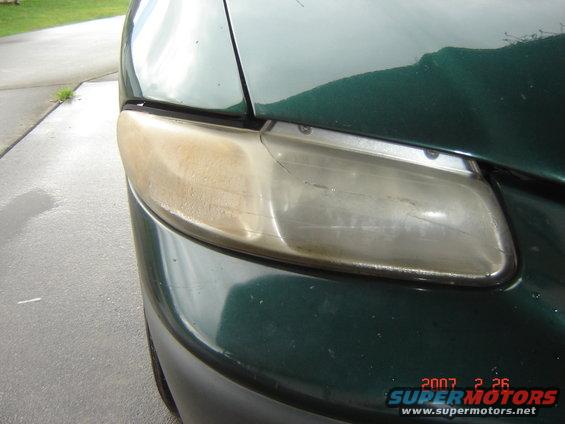Green minivan headlight with yellowed plastic and visible cracks