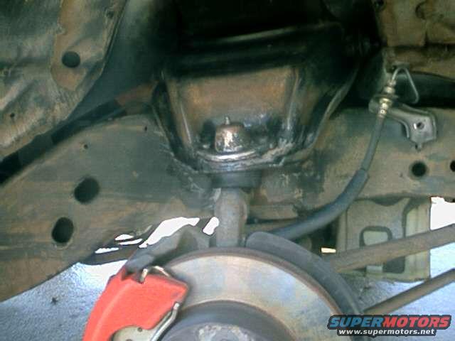Underside of a vehicle showing suspension components, brake rotor, and caliper
