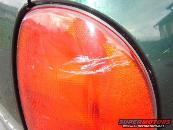 Green minivan taillight with scratches and scuffs, close-up