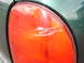 1997 Dodge Grand Caravan - A close-up of a damaged green minivan taillight shows significant scuffing and scratches on the red lens.