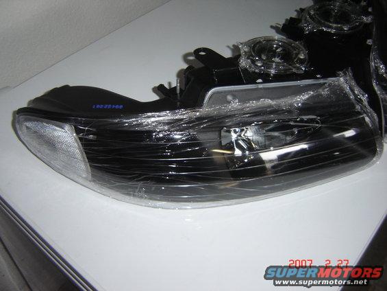 Car headlight assembly wrapped in plastic. Blue text reads '10022500'