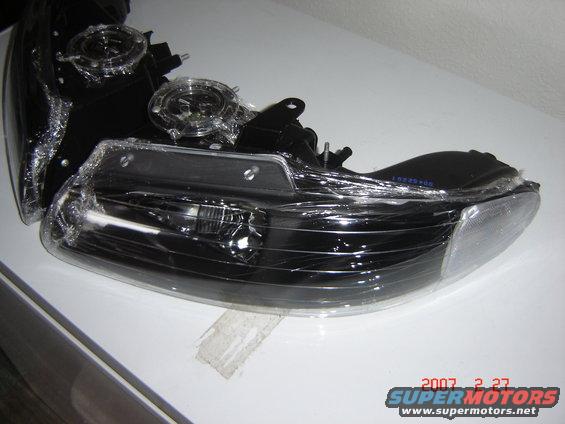 Two black headlights wrapped in plastic, one partially obscuring the other