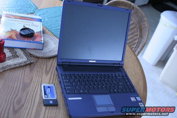 Blue Sony VAIO laptop on a wooden table with a book and a memory card
