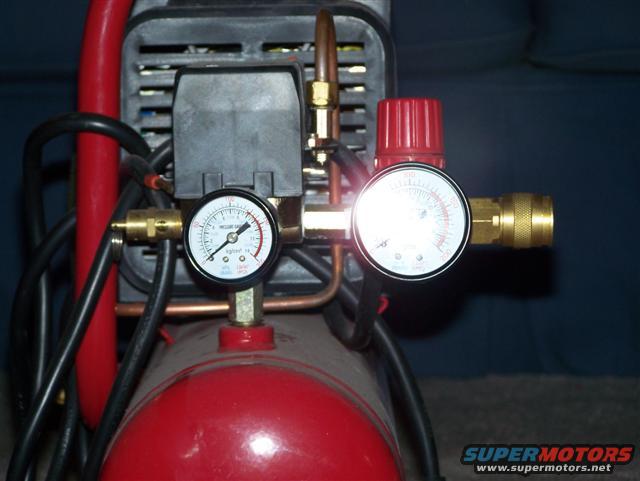 air compressor with two pressure gauges and a red regulator knob