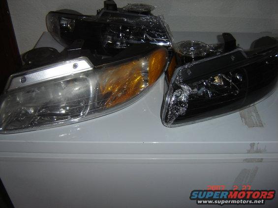 Two new car headlights, one clear and amber, one blacked out