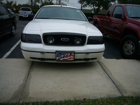 White Ford Crown Victoria front view with blacked-out headlights and grille, D.A.R.E. license plate