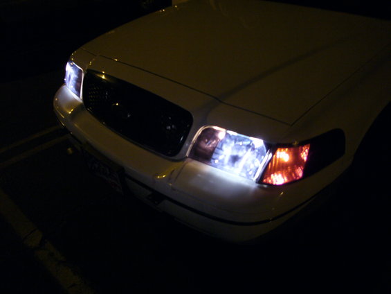 White 2000 Ford Crown Victoria front end with headlights on, angled slightly from the front