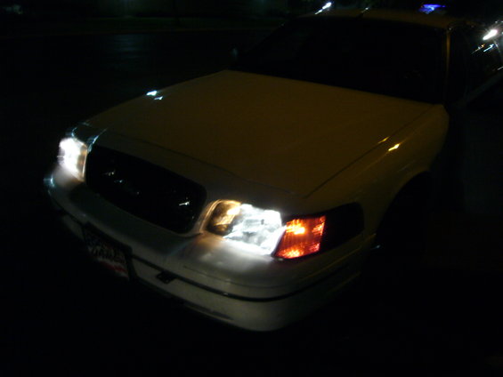 Front view of a white 2000 Ford Crown Victoria with headlights on