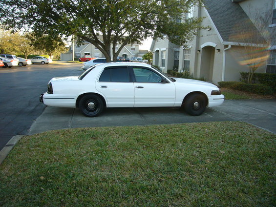 White 2000 Ford Crown Victoria sedan parked on asphalt, side view, black steel wheels, tinted windows