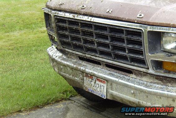 Brown Ford truck front end covered in mud, showing grille and license plate