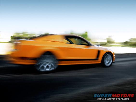 Orange sports car speeding down a road, motion blur on wheels and background