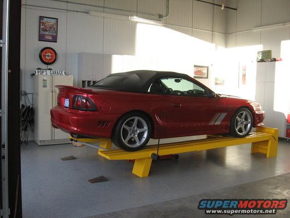 Red convertible Mustang on a yellow lift