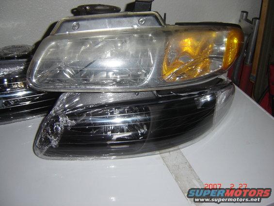 Two car headlights, one clear and one blacked-out, stacked on a white surface