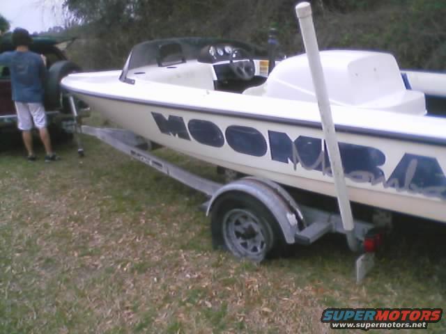 White boat with blue lettering 'MOOMBA' on a trailer, parked on grass