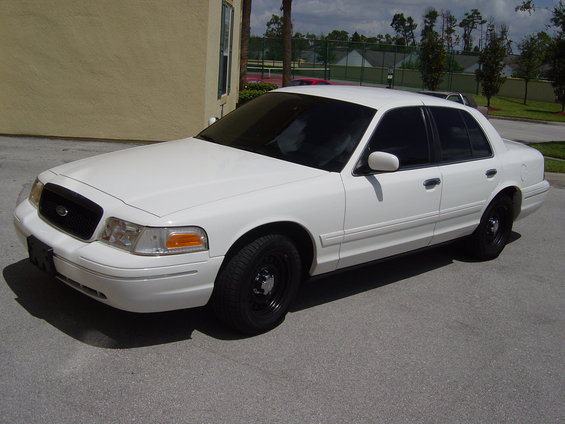 White 2000 Ford Crown Victoria sedan, front 3/4 view, black steel wheels, tinted windows, parked on asphalt