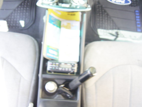 Car interior showing a center console with a radio, gear shift, and papers