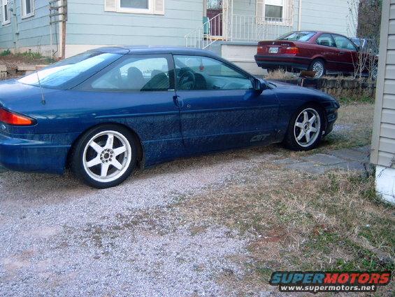 Blue 1994 Ford Probe GT parked next to a house, with a red BMW in the background