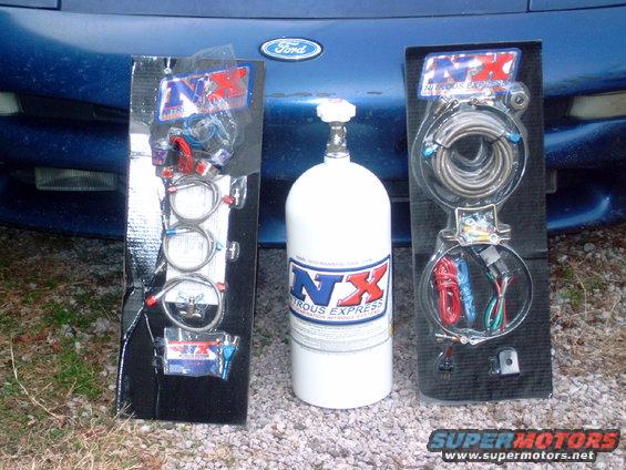 Nitrous Express bottle and two kits laid out in front of a blue Ford vehicle