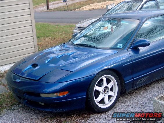 Blue 1994 Ford Probe GT with aftermarket hood scoop and white wheels, parked next to another car