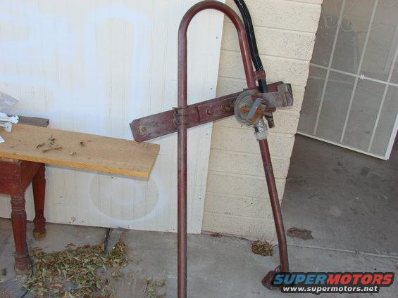 Red metal part with hoses and a circular component, resting on concrete
