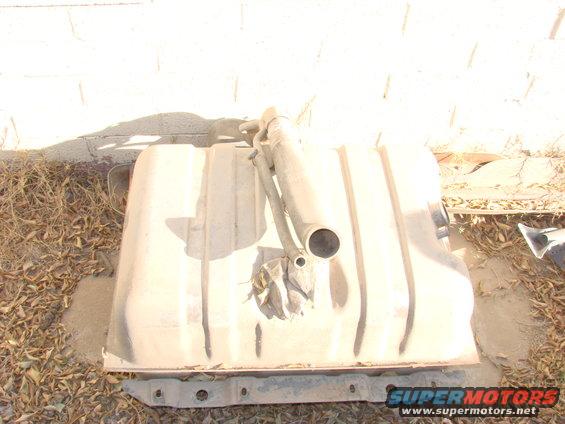 Tan fuel tank with metal straps and filler neck, resting on the ground