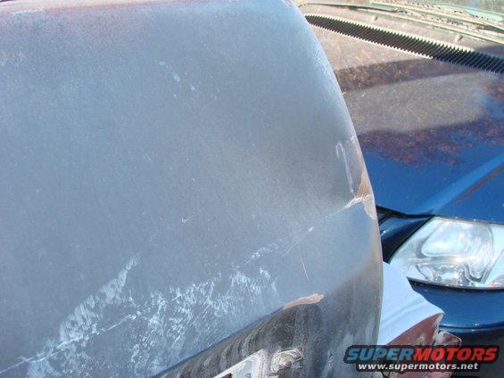 Close-up of a weathered vehicle body panel next to another vehicle's headlight