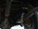 1996 Ford Bronco - Underside view of vehicle suspension components, showing driveshaft, leaf springs, and shock absorber.