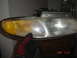 1997 Dodge Grand Caravan - A gloved hand holds a car headlight assembly, showing its aged and weathered condition.