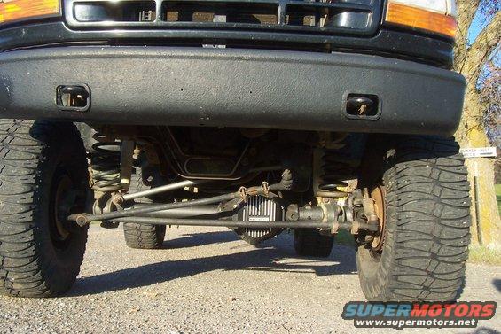Low angle shot of a truck's front axle, suspension, and large tires