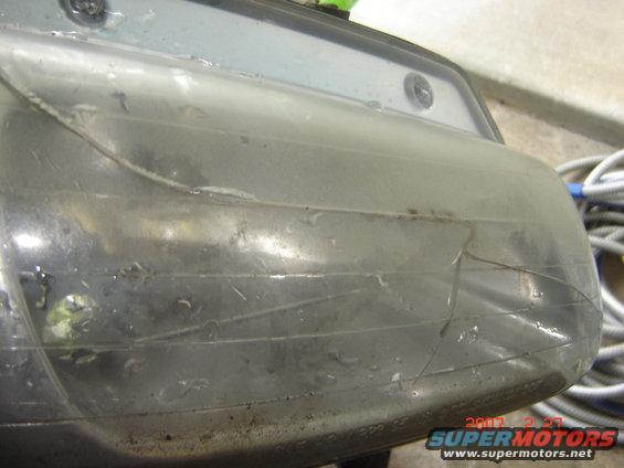 Close-up of a dirty, cracked headlight assembly with visible internal wiring