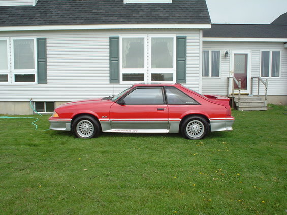 Red 1989 Ford Mustang GT side view with silver trim