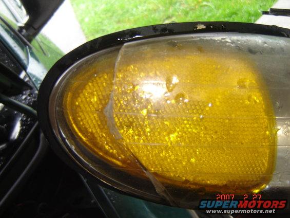 Yellow headlight assembly with cracked plastic cover and water droplets