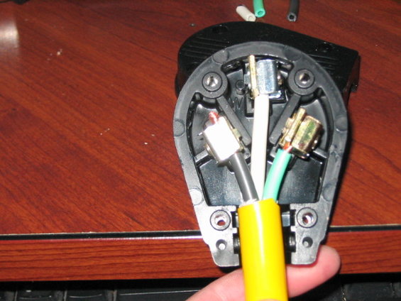 Wiring inside a black electrical plug with yellow, white, and green wires connected