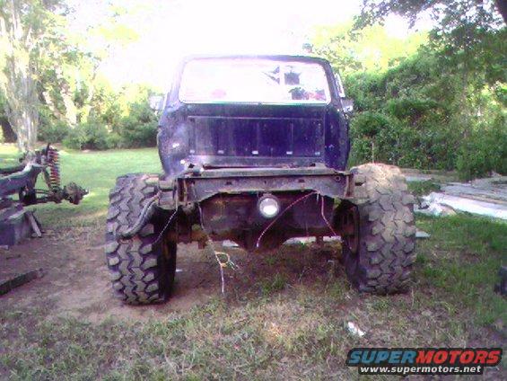 Rear view of a dark blue pickup truck chassis with large off-road tires and no bed