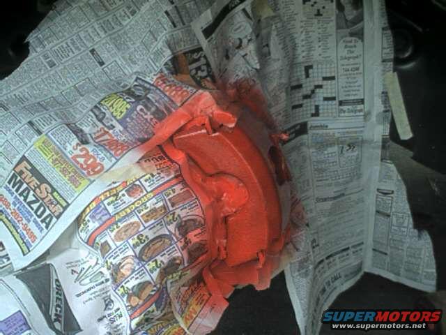 Red painted brake caliper wrapped in newspaper