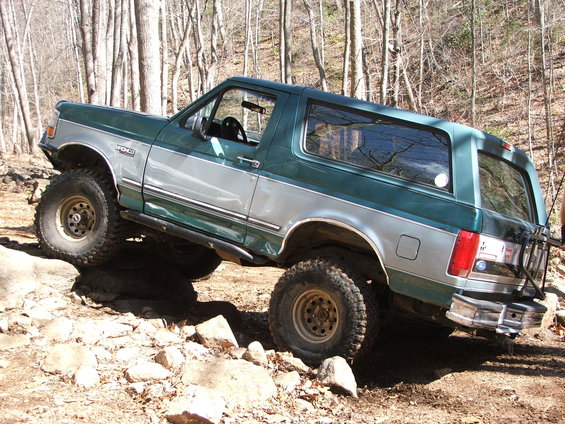 Green and silver Ford Bronco off-roading over rocks