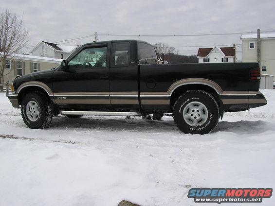 Black pickup truck with tan trim, side view, in snow