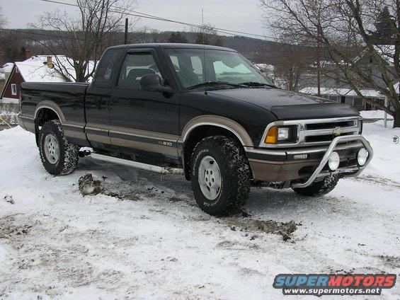Black 1996 Chevrolet S-10 pickup truck with a chrome bull bar and fog lights, parked in snow