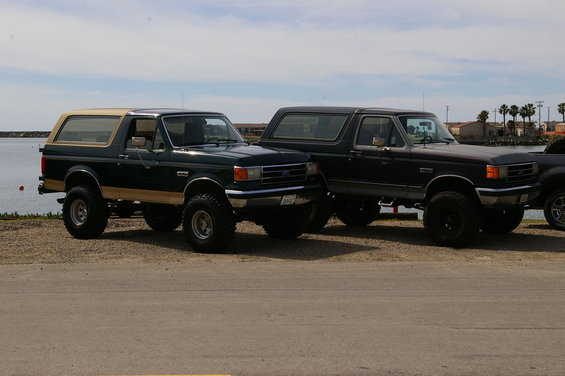 Dark green and tan Ford Bronco parked next to a dark blue Ford Bronco