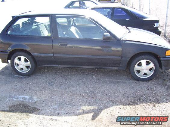 Side view of a dark hatchback with a black car behind it