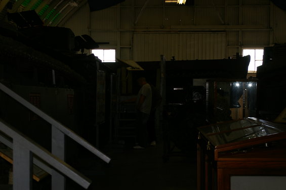 Interior of a museum or warehouse with exhibits and a person standing near stairs