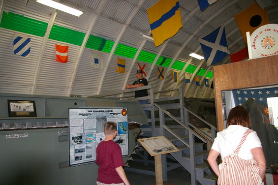 Museum interior with nautical flags, exhibits, and people viewing displays
