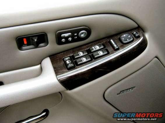 Interior door panel of a 2002 GMC Yukon Denali with wood trim, power window controls, and a Bose speaker