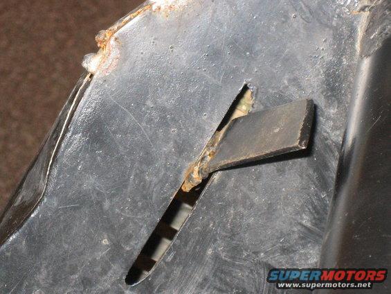 close-up of a rusted metal piece with a rectangular slot cut into it, showing some wear and tear