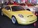 1997 Ford Taurus - A yellow concept car is displayed indoors, with another vehicle visible behind it.