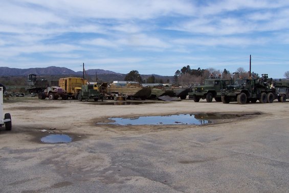 Several military trucks parked in a lot with puddles
